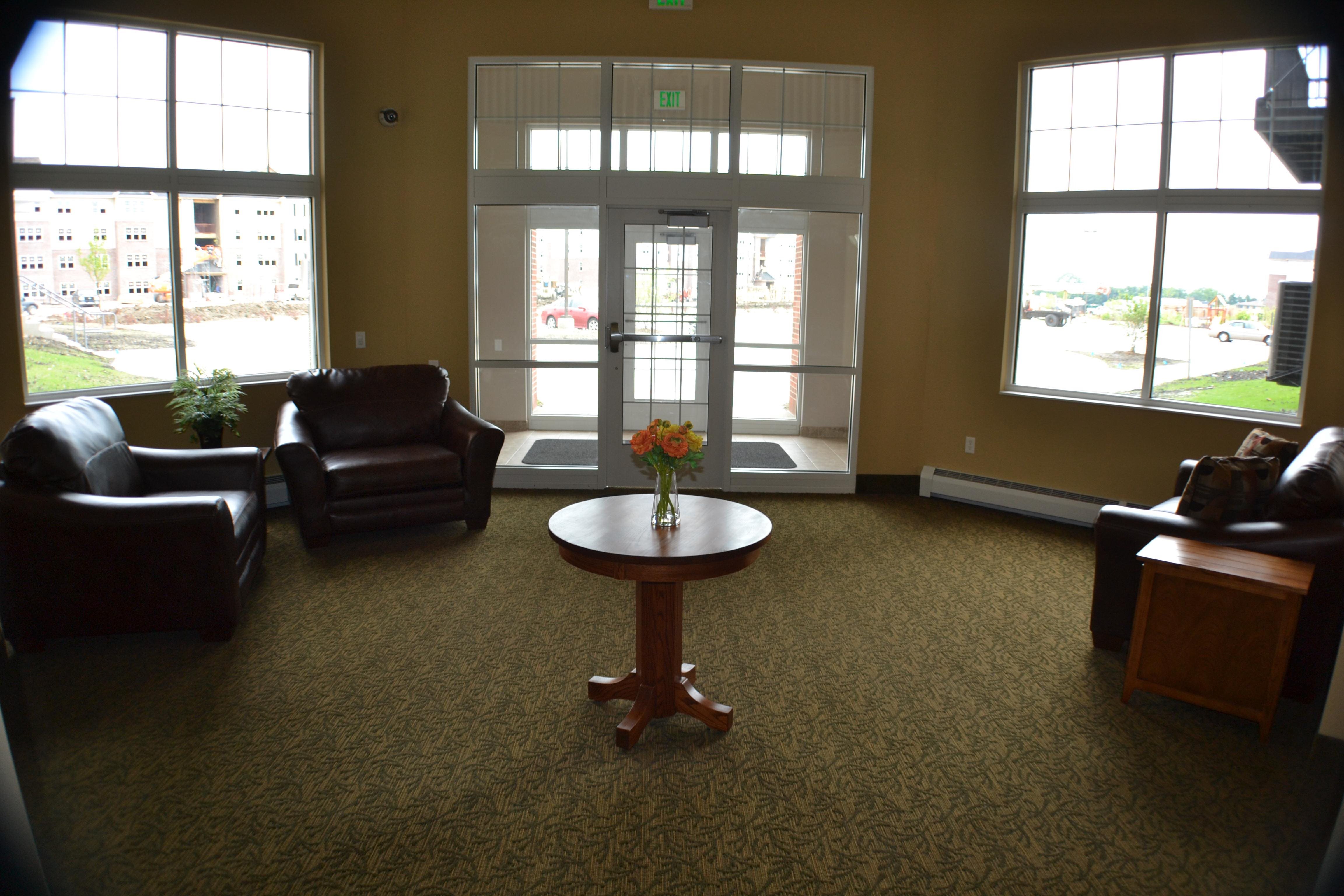 A waiting room with a table in the middle and chairs around it.,A waiting room with a table in the middle and chairs around it.